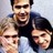 Pixelated static image of three people in a group pose with neutral to smiling expressions on a light gray background.