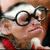 Pixelated static image of a person with light skin, dark hair, and round black glasses, wearing a red garment with white accents, set against a brown background.