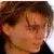 Pixelated close-up of a person's face with brown hair, showing partial facial features and a dark garment at the bottom edge.