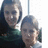 Two pixelated figures with dark hair and green clothing appear in close proximity, one slightly behind the other against a bright background.