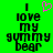 Green background with black pixelated text reading "I love my gummy bear" and a pink heart symbol above the word I.