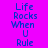 Pixelated text "Life Rocks When U Rule" on a split purple background with cyan and magenta sections.