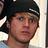 Pixelated close-up of a person wearing dark headwear with light accents, set against a blurred background.