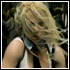 A blonde woman with long hair performs a sequence of dance moves in an indoor venue, wearing a white tank top and black pants.