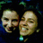 Two stylized human faces with exaggerated features against a dark background with green and blue pixelated accents.