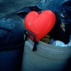 A red heart-shaped icon with a black outline is centered on a person's chest, partially obscured by a dark jacket and light-colored shirt.