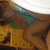 A person in a green bikini top and brown bottoms lies on a patterned surface with a white curved shape above, showing a slight shift in leg position across frames.