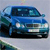 Blue sedan vehicle with headlights on, front-facing view, visible license plate, dark tinted windows, and visible front bumper.