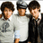 Three pixelated figures with dark hair stand side-by-side; the central figure wears a cap and light shirt, while left and right wear darker tops.