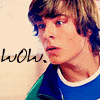 A pixelated close-up of a person with light brown hair wearing a blue and green shirt, with the word 'wow.' in black script on the left side of the image.