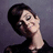 Pixelated image of a person with short dark hair and glasses, wearing a black top against a purple background, with overlaid text reading 'EATING breakfast at TIFFANY'S', 'WAS just not ENOUGH', and '[*AUDREY*] HEPBURN'.