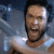 Pixelated static image of a person with short dark hair and a beard, wearing a light-colored sleeveless top against a blurred blue-gray background.