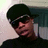 A pixelated close-up of a person wearing a dark cap and shirt, with visible facial features against a blurred background.
