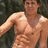 Static pixelated image of a shirtless person with light skin tone, visible chest and abdominal muscles, and a neutral expression against a dark background.