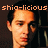 Pixelated close-up of a person's face with orange-toned skin, dark hair, and a dark background, overlaid with orange text reading 'shia-licious'.