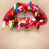 Red lips covered in colorful sprinkles against a light brown background.