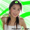 A person with long dark hair in a side braid wears a white sleeveless top and colorful earrings, standing against a green and white striped background with a green crown icon above their head.