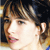 Pixelated close-up of a person's face with brown hair and pink lips against dark background, static single-frame image.