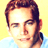 Static pixelated image of a person's face with brown hair and light skin against a yellow background, wearing a blue garment at the bottom edge.