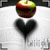 A red and green apple sits above a black heart on a white background with faint gray text.