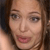A pixelated close-up of a person's face with brown hair, light skin, and pink lips, showing a neutral expression with eyes looking slightly left.