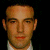 A pixelated image of a person with short hair and light skin wearing a white shirt, next to green text reading 'Original Icons .com' on a dark background.