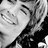 Black-and-white pixelated image of a smiling person with closed eyes and visible teeth, cropped to show upper body and hair.