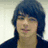 Pixelated image of a person with dark blue hair and a dark shirt, surrounded by pink text on black background.