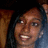 Pixelated close-up of a person with dark hair, light skin tone, and visible teeth in a wide smile against a blurred background.