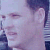Pixelated close-up of a person's face with light skin tone, dark hair, and closed eyes, set against a blurred background with purple and blue hues.