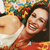 A pixelated image shows two people in close proximity, one holding a bouquet of flowers with green leaves and red and yellow blooms, while the other wears a white top and red garment.