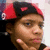 Pixelated close-up of a person wearing a red and black hat with white accents, set against a light background.
