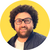 Pixelated circular icon shows a person with dark curly hair, glasses, and beard against yellow background wearing dark jacket over light shirt.