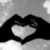 Black and white pixelated image showing two hands forming a heart shape with fingers, set against a light gray background.