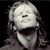Pixelated grayscale image of a figure with long hair, closed eyes, and an open mouth against a black background.