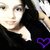Pixelated close-up of a person with dark hair wearing black clothing, holding an object near their face, and a purple heart symbol in the bottom right corner.