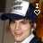 Animated sequence showing a person in dark blue cap with white front and repeated text, wearing dark jacket over light shirt against brown background; heart symbol changes from white to red