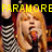 Pixelated image of a person with long blonde hair singing into a microphone, wearing a black and white checkered top, under yellow text reading "PARAMORE ROCKS!!!".