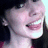 Pixelated close-up of a person with light skin and dark hair, mouth open in a wide smile showing teeth, against a dark background.