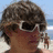 Pixelated beach scene with two identical figures wearing sunglasses and brown hair, one figure has cyan text overlay.