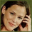 Two side-by-side pixelated images of a person with brown hair, one showing hand near face and the other smiling broadly.