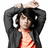 Pixelated image of a person with dark hair wearing a black jacket over an orange striped shirt, hands raised above head.