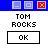 Pixelated graphic with blue header containing three square icons, central text reading TOM ROCKS above a black-outlined button labeled OK.