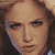 A pixelated image of a person with brown hair wearing a blue and white striped jacket, holding an object near their face.