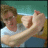 A person in a white shirt and blue pants performs arm movements against a teal background with yellow accents.