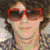 Six- shows a person with curly hair in various poses with orange text listing reasons for liking Nick Jonas