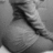 Black-and-white image of a person's lower back and buttocks in motion, wearing dark pants with visible creases.