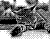 Pixelated grayscale image of a figure in motion with blurred limbs and indistinct facial features against a checkered background.