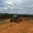 Pixelated landscape showing a vehicle on brown terrain under gray sky with distant horizon line.