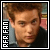Pixelated portrait of a person with light brown hair and fair skin, wearing a dark jacket over a light shirt, with vertical text on the left side.